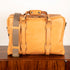 Tan leather bag with straps on a wooden surface
